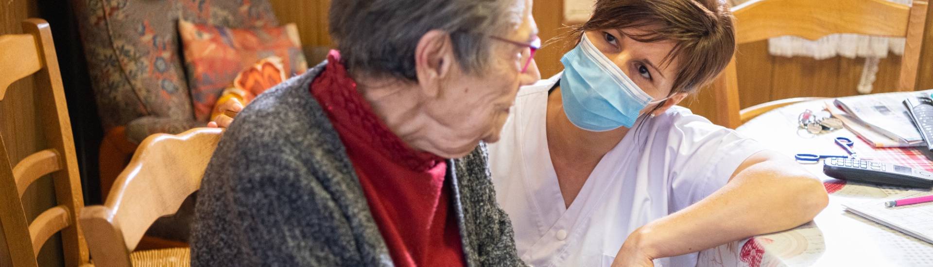 aide soignante se met à la hauteur de la patiente et discute