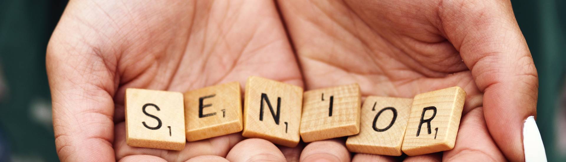 Lettres du jeu scrabble dans une main qui représentent le mot "sénior"