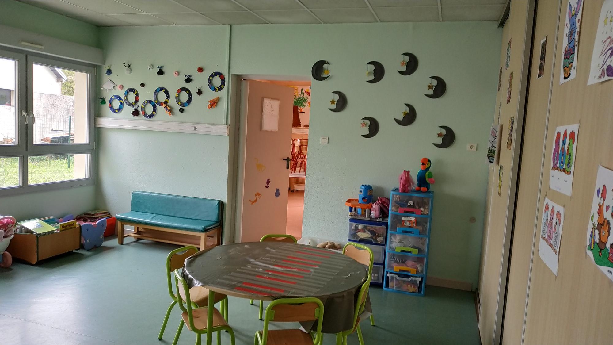pièce aves tables et chaises pour enfants et dessins accrochés sur les murs 