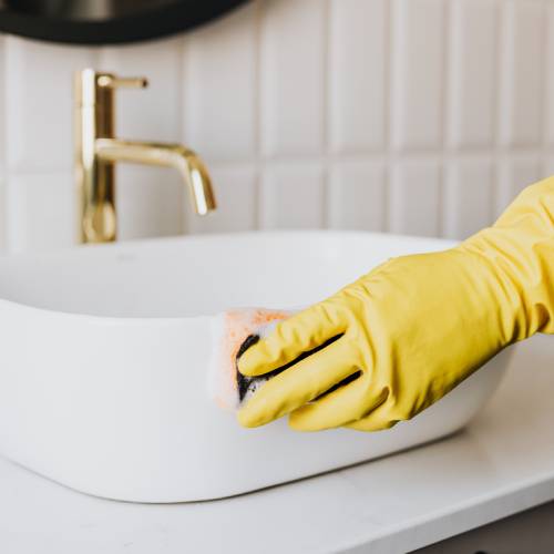 main ganté qui nettoie un lavabo
